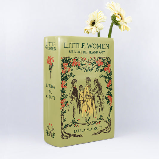 Little Women ceramic book vase with floral design and two white flowers against white background