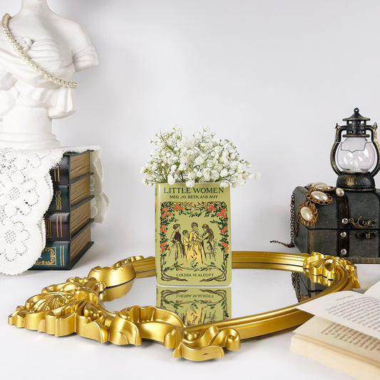 Little Women book vase with white flowers on a gold mirror, vintage books, and pearl statue decor